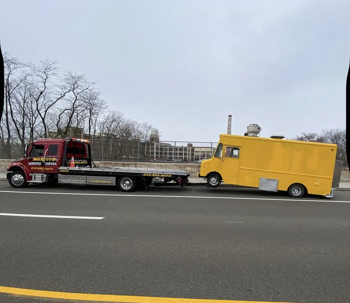 A box truck under tow by a Mr. Kitt's medium duty unit