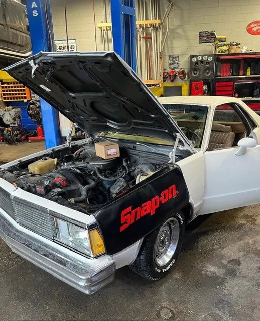 A classic car with the hood up on the shop floor at Mr. Kitt's