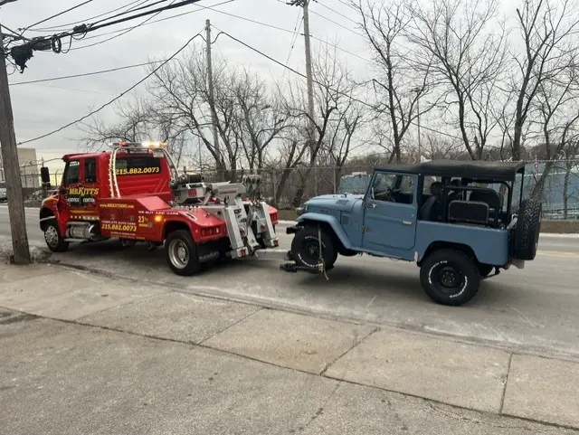 A Mr. Kitt's wrecker towing a four wheel drive off the street