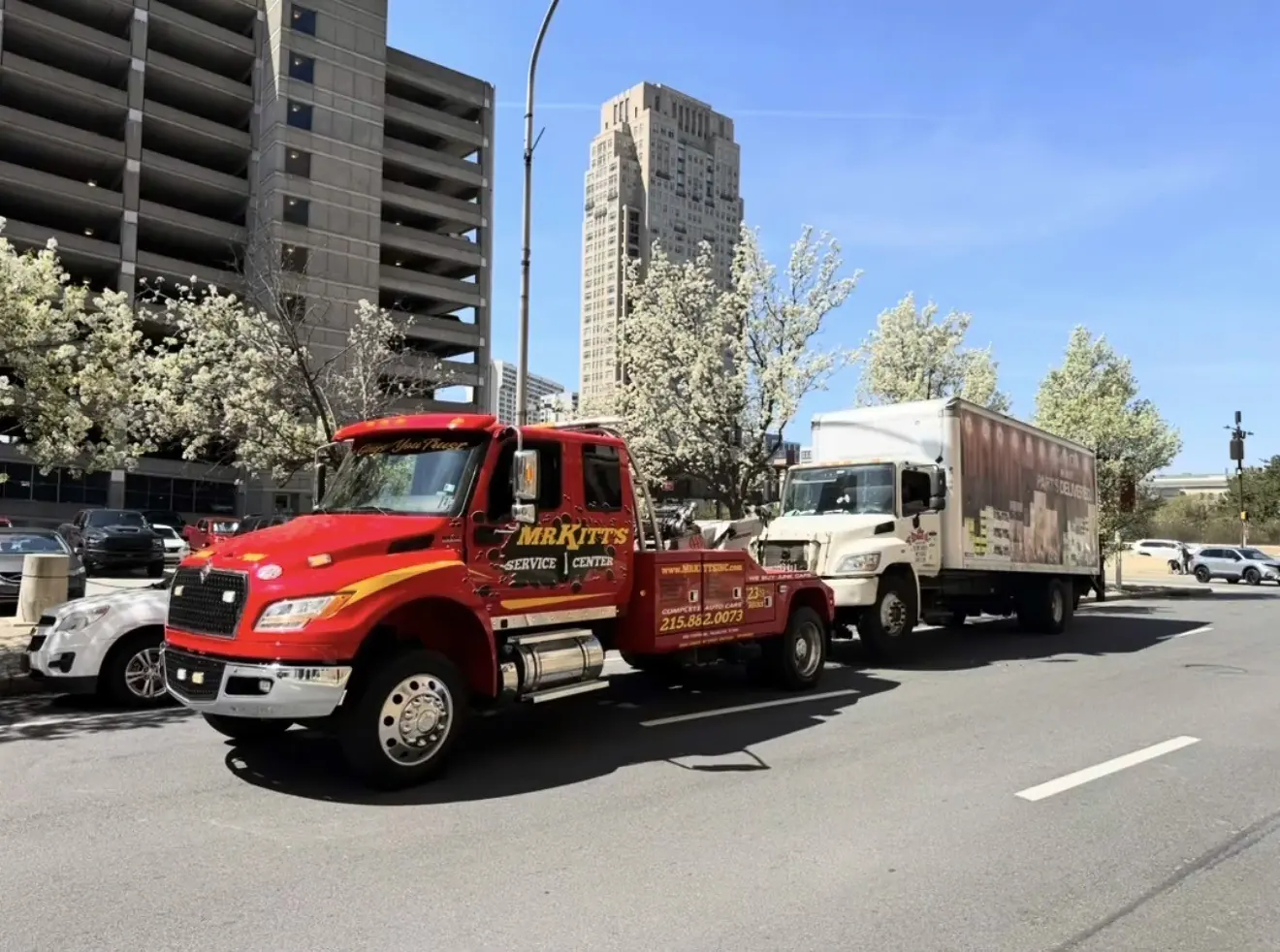 A Mr. Kitt's medium duty wrecker towing a box truck through Philadelphia